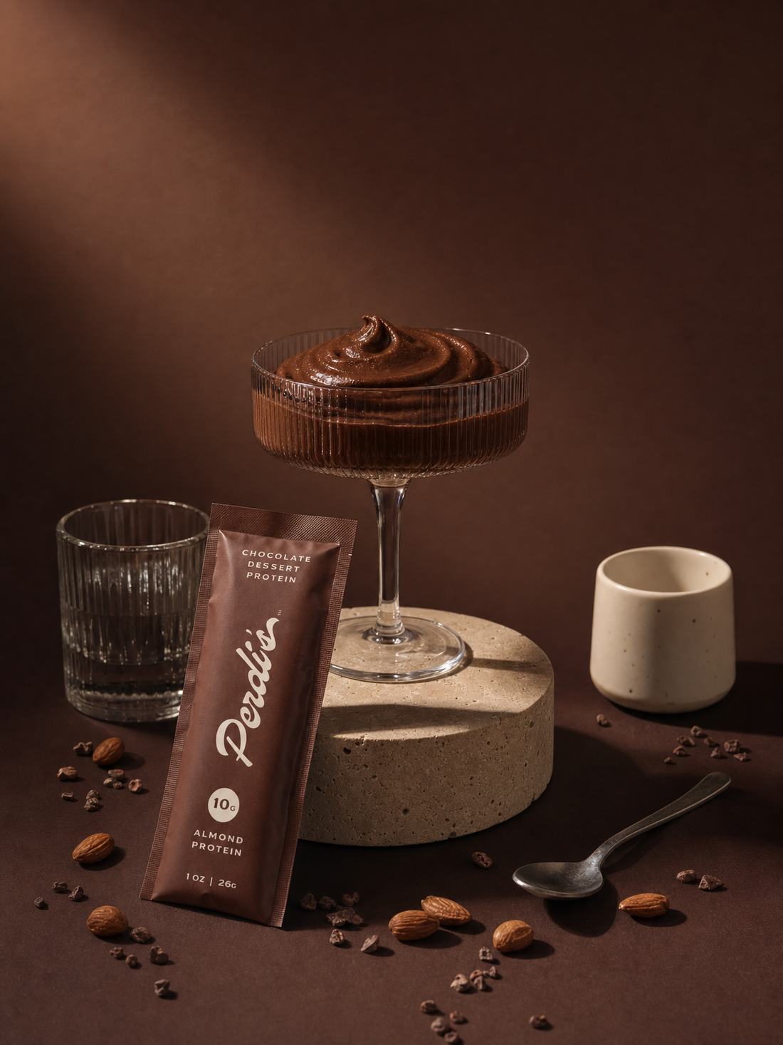 Coupe of chocolate pudding displayed on a stone pedestal beside a Perdi's packet